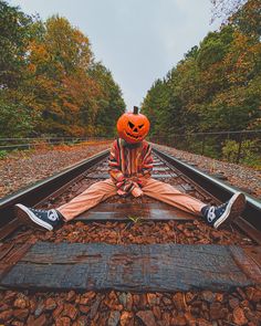 a person sitting on train tracks with a jack - o'- lantern in the middle