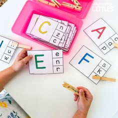 hands holding clothes pegs and matching letters to match them up with the letter recognition game