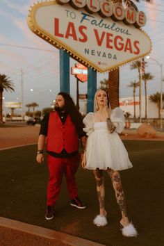 a man and woman posing in front of the welcome to fabulous las vegas sign