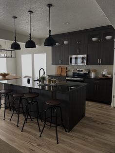 a kitchen with an island and bar stools next to the stove top oven in it