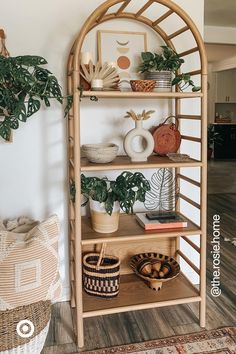 a bamboo shelf with plants and baskets on it in the corner of a living room