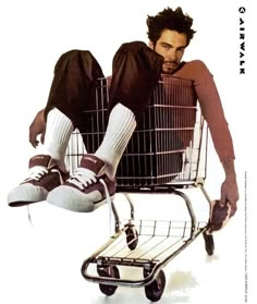 a man sitting in a shopping cart with his feet up on the top of it