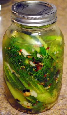 a jar filled with green vegetables on top of a counter