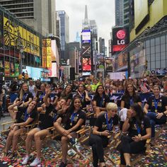 a group of women sitting on top of a pile of skateboards in the middle of a city