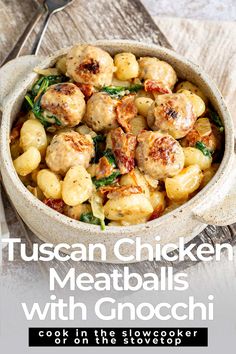 a white bowl filled with meatballs and spinach on top of a wooden table