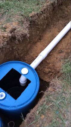 a blue and white pipe laying in the ground next to a hole with water coming out