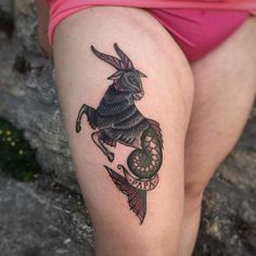 a woman's thigh with a tattoo of a goat and snake on the side