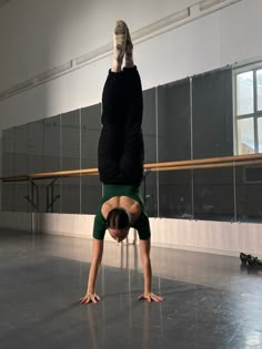 a woman is doing a handstand on the floor in an empty room with mirrors