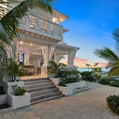 an oceanfront home with steps leading to the front door and palm trees surrounding it