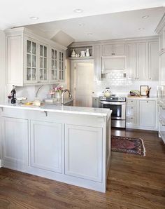 a kitchen with white cabinets and wood floors