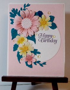 a birthday card with flowers on it sitting on top of a wooden easel next to a wall