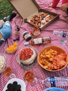 a picnic table with food, drinks and snacks laid out on the grass in front of it