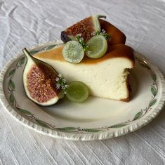 a piece of cheesecake with grapes and kiwis on a white table cloth