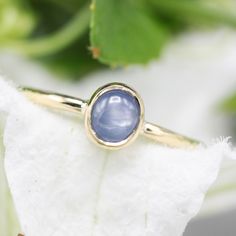 a gold ring with a blue stone on it sitting on top of a white flower