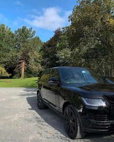 a black range rover parked in front of some trees