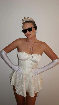 a woman wearing white gloves and a tiara is listening to music on her headphones