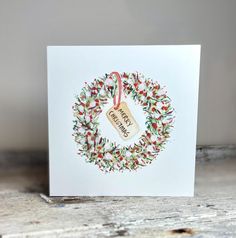 a white card with a christmas wreath on it and a tag hanging from the front