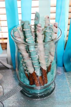 there are many donuts in the glass vase on the table with blue streamers