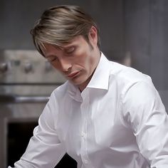 a man in a white shirt and tie preparing food