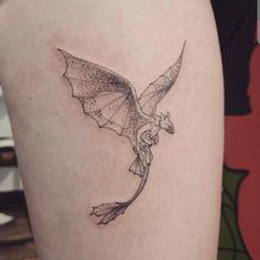 a black and white photo of a dragon tattoo on the thigh, with wings spread out