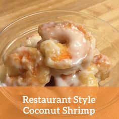 a glass bowl filled with donuts covered in icing and orange glaze on top of a wooden table