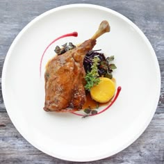 a white plate topped with meat and veggies on top of a wooden table