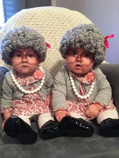 two baby dolls sitting on top of a gray couch next to each other wearing glasses