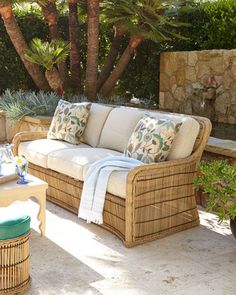 an outdoor living area with wicker furniture and palm trees in the background, along with potted plants