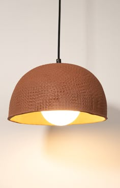 a brown lamp hanging from a ceiling with a white light on the top and bottom