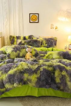 a bed covered in green and purple fur with a stuffed animal sitting on top of it