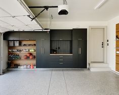 an empty garage with black cabinets and white flooring on the outside wall, along with hanging lights