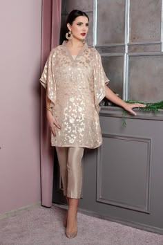 Model: 174 cm and 61 kg size M Opting for relaxed kaftan style for daytime ease, elegantly draped dress for evening festivity. This fawn coloured, brocade fabric flower printed dress had draped sleeves tailored for perfect and unique look. Provided with raw silk lining and edging all over the outfit and sultry V-neck is a visual delight for the eyes. Slim straight pure silk pants complete the beautiful dress. It can be styled in numerous ways to create stellar looks that are perfect for all occasions from lunch with the girls to evening soirees. Top: Color: Fawn   Fabric: Brocade  Golden floral printed kaftaan  Silk edge finish  Silk lining inside  V-neck   Bottom: Color: Fawn   Fabric: Silk Slim pants  Half elasticated waist Gharara Saree, Ladies Suit, Kaftan Designs, Ritu Kumar, Pakistani Dresses Casual, Pakistani Fashion Party Wear, Solange Knowles, Pakistani Dress, Simple Pakistani Dresses