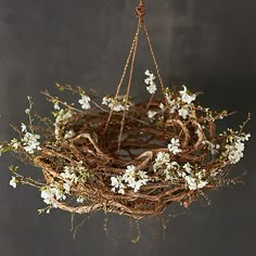 a wreath hanging from a rope with white flowers and branches in the shape of a bird's nest