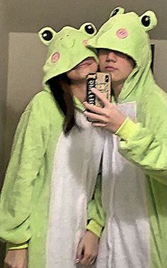 a woman in a frog costume taking a selfie with her cell phone while holding a can