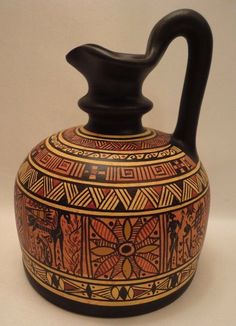 an artisticly designed vase with a black handle