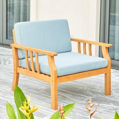 a wooden chair sitting on top of a hard wood floor next to plants and flowers