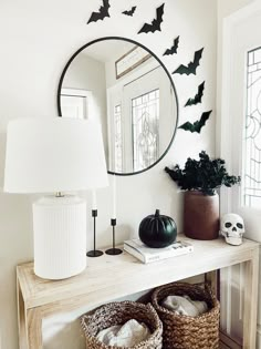 a white table topped with two baskets filled with bats next to a mirror and lamp