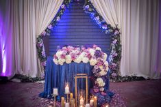 a table with candles and flowers on it in front of a brick wall at a wedding