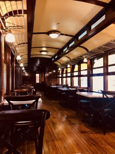 the inside of a train car with tables and chairs on it's sides, along with wooden flooring