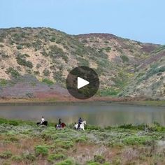 three people riding horses in front of a lake and mountains with a video screen showing them