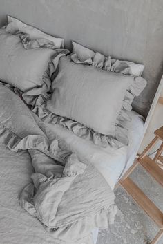 an unmade bed with ruffled sheets and wooden chair next to it on the floor