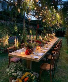 a long table with candles and flowers on it in the middle of an outdoor garden