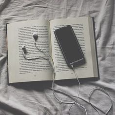 an open book with headphones and earbuds laying on top of the book