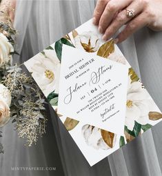 a person holding a wedding card with flowers on it and the bride's hand