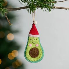 an ornament hanging from a tree branch with a christmas hat on it's head