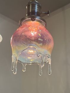 a glass light fixture hanging from the ceiling with icicles on it's bottom