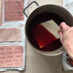 a person is holding a piece of paper in a pot full of liquid on a table