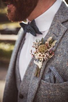 a man wearing a suit and bow tie with a boutonniere on his lapel