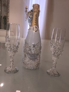 three wine glasses and a champagne bottle on a table with a mirror in the background