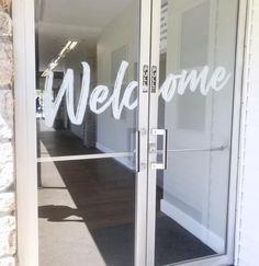 an open glass door with the words welcome on it